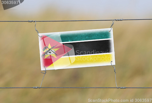 Image of Border fence - Old plastic sign with a flag