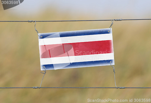 Image of Border fence - Old plastic sign with a flag