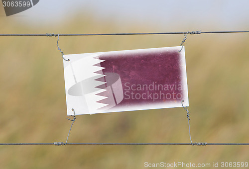 Image of Border fence - Old plastic sign with a flag