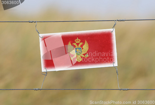 Image of Border fence - Old plastic sign with a flag