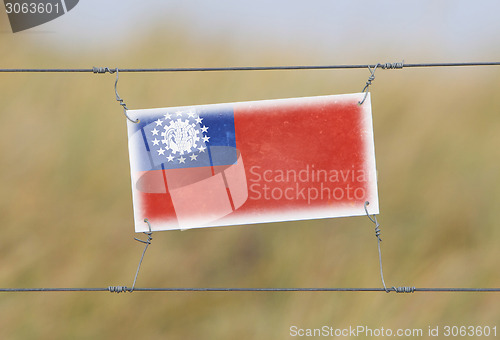 Image of Border fence - Old plastic sign with a flag