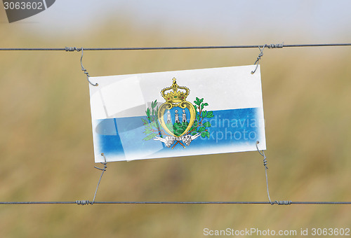 Image of Border fence - Old plastic sign with a flag