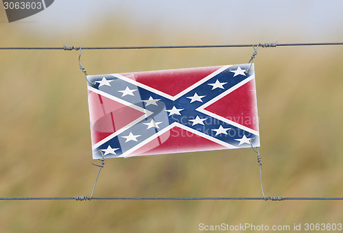 Image of Border fence - Old plastic sign with a flag