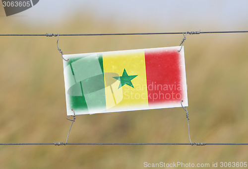 Image of Border fence - Old plastic sign with a flag