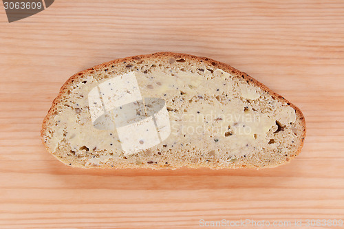 Image of Slice of buttered bread on a wooden table