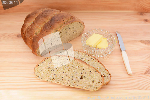 Image of Fresh bread with butter and knife on a wooden table