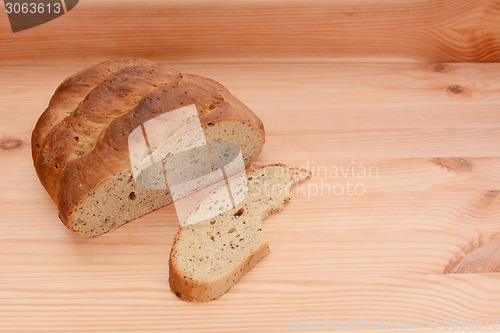 Image of Half-eaten loaf of bread on a table with a cut slice