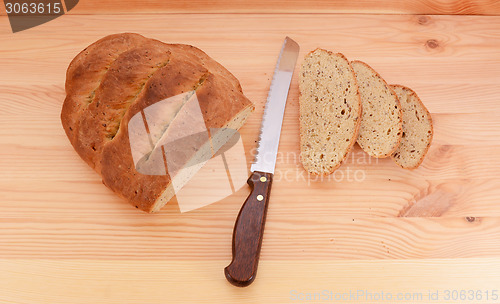 Image of Fresh loaf of bread with a knife and three slices