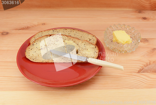 Image of Buttered slices of bread on a red plate 