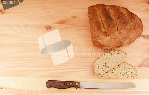 Image of Fresh loaf of bread, cut slices and bread knife