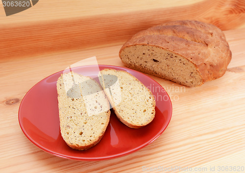 Image of Two slices of bread on a red plate, with a loaf of bread