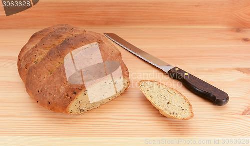 Image of Freshly baked loaf of bread and bread knife on the table