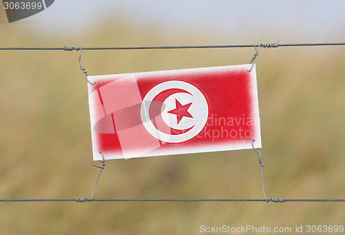 Image of Border fence - Old plastic sign with a flag