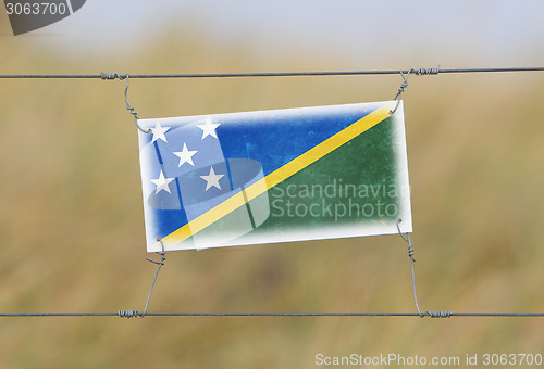 Image of Border fence - Old plastic sign with a flag