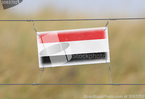 Image of Border fence - Old plastic sign with a flag