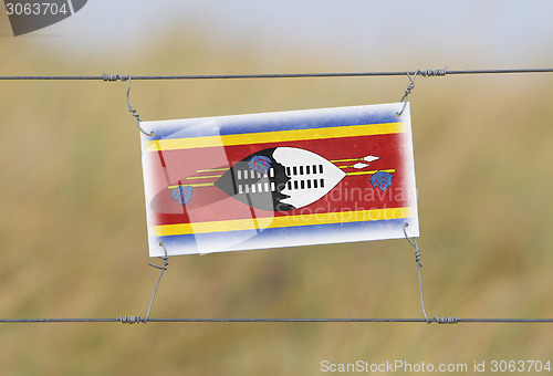 Image of Border fence - Old plastic sign with a flag