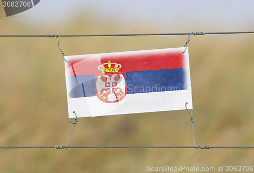 Image of Border fence - Old plastic sign with a flag