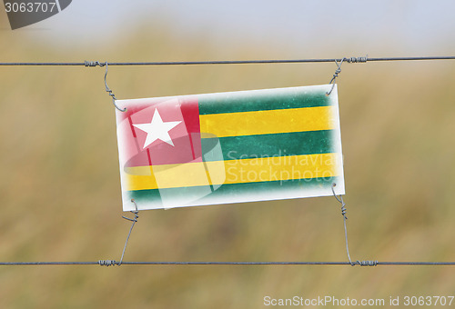 Image of Border fence - Old plastic sign with a flag