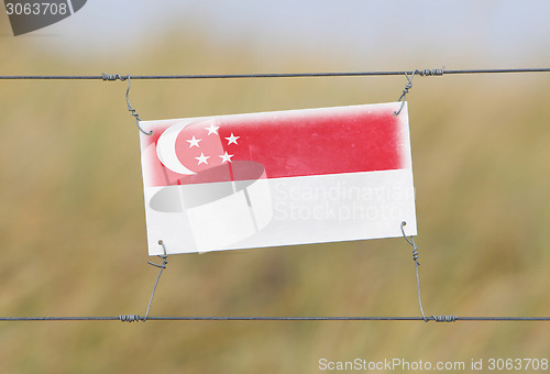 Image of Border fence - Old plastic sign with a flag