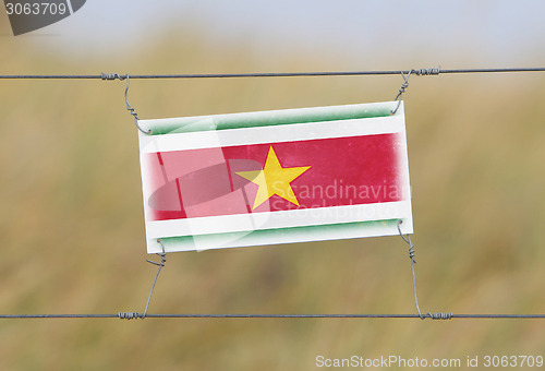 Image of Border fence - Old plastic sign with a flag