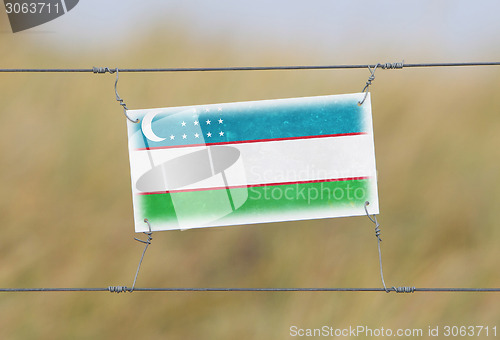 Image of Border fence - Old plastic sign with a flag