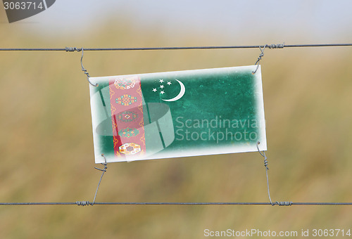 Image of Border fence - Old plastic sign with a flag