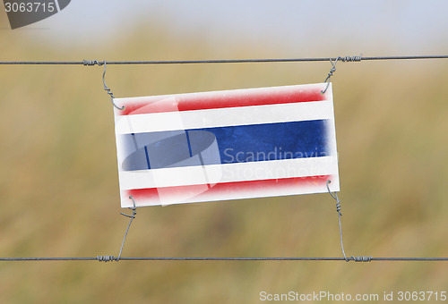 Image of Border fence - Old plastic sign with a flag