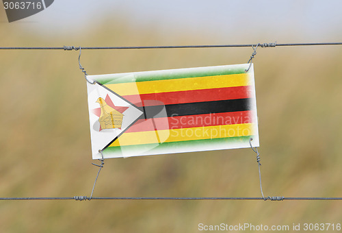 Image of Border fence - Old plastic sign with a flag