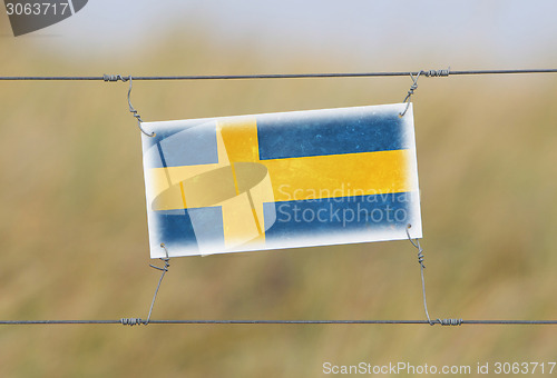 Image of Border fence - Old plastic sign with a flag