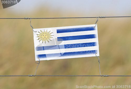 Image of Border fence - Old plastic sign with a flag