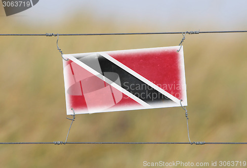 Image of Border fence - Old plastic sign with a flag