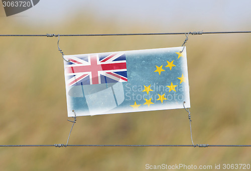 Image of Border fence - Old plastic sign with a flag