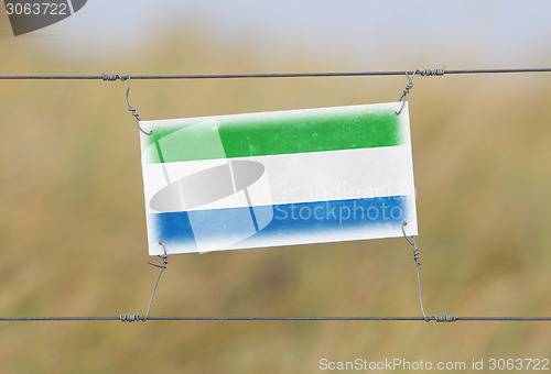 Image of Border fence - Old plastic sign with a flag