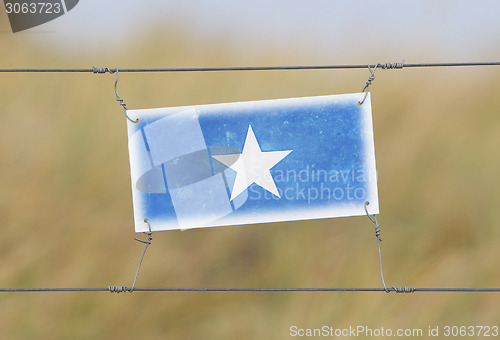 Image of Border fence - Old plastic sign with a flag