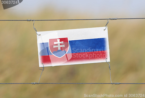 Image of Border fence - Old plastic sign with a flag