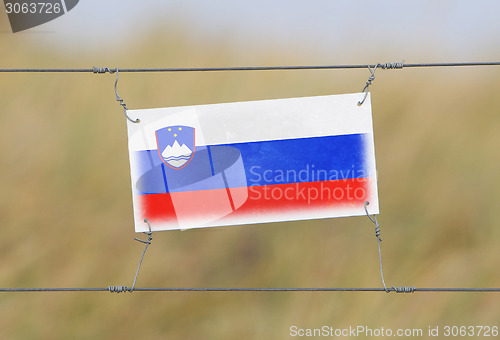 Image of Border fence - Old plastic sign with a flag