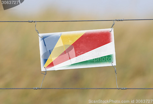 Image of Border fence - Old plastic sign with a flag