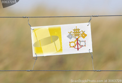 Image of Border fence - Old plastic sign with a flag