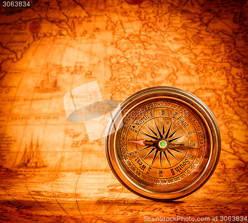 Image of Vintage compass lies on an ancient world map.