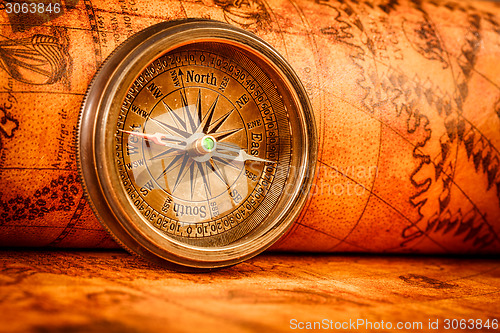 Image of Vintage compass lies on an ancient world map.