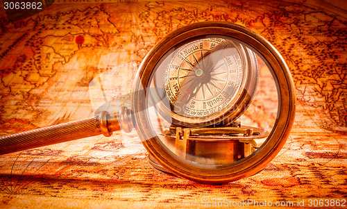 Image of Vintage magnifying glass lies on an ancient world map