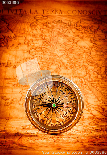 Image of Vintage compass lies on an ancient world map.