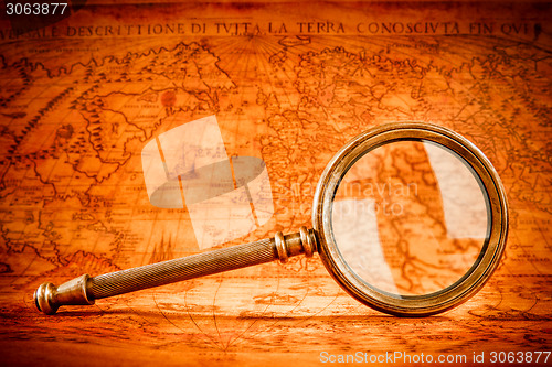 Image of Vintage magnifying glass lies on an ancient world map