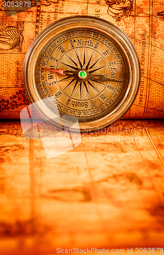 Image of Vintage compass lies on an ancient world map.