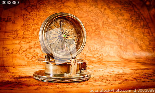 Image of Vintage compass lies on an ancient world map.