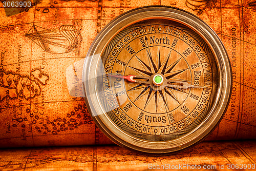 Image of Vintage compass lies on an ancient world map.