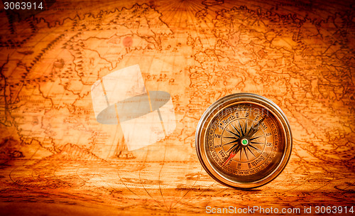 Image of Vintage compass lies on an ancient world map.