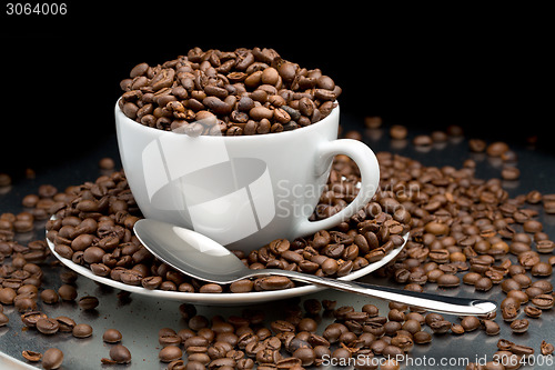 Image of Cup and saucer full of coffee beans with a spoon