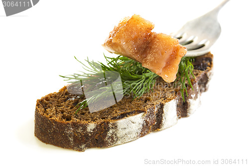 Image of Slice on a fork herring and black bread.