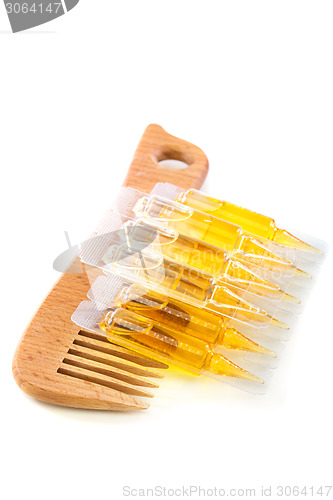 Image of Hair oil and wooden comb.